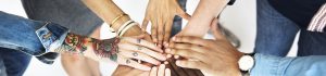 A diverse group of people all putting their hands together.